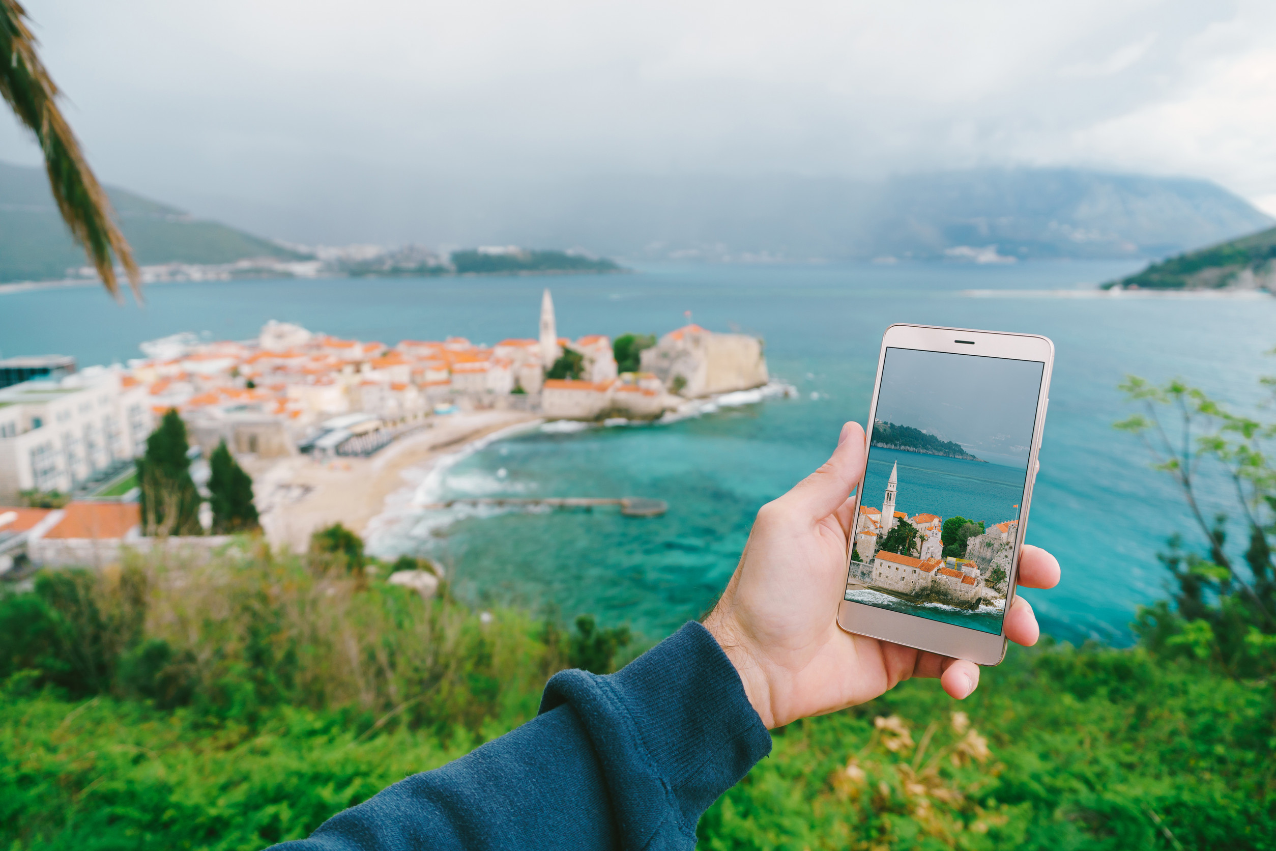mans hand holds a smartphone with a photo of architecture left the old town mans hand holds a smartphone with a photo of architecture left the old town